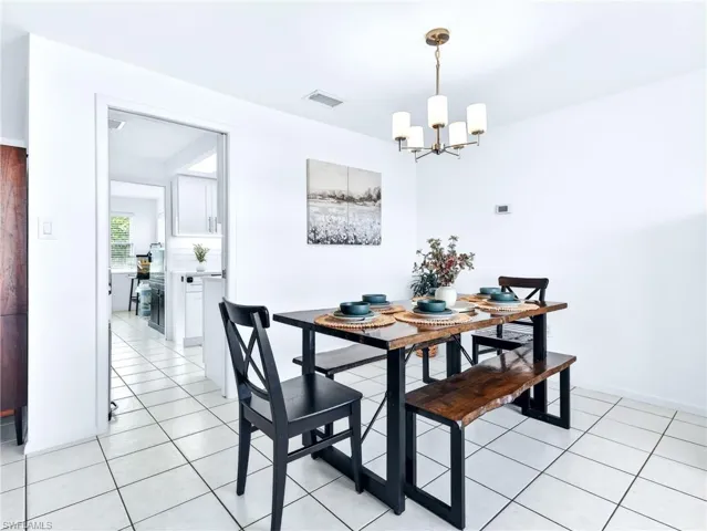 Dining area featuring white square tile flooring and a bronze five-light chandelier