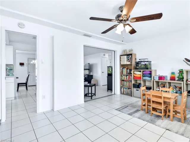 Bright room featuring tile flooring, a ceiling fan with light fixture, and an open doorway to an additional space