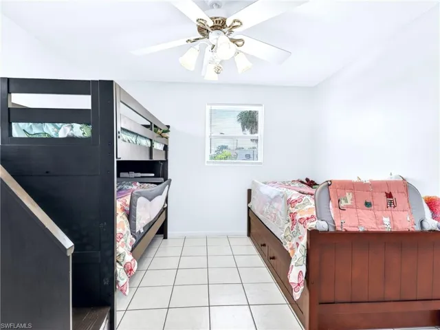 Room featuring neutral wall paint, square tile flooring, a window with blinds, and a ceiling fan with integrated lighting