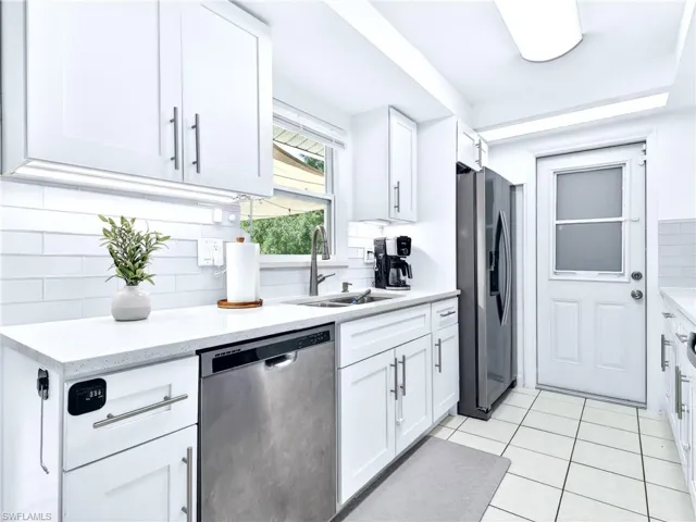 Bright kitchen featuring white shaker cabinetry with brushed nickel hardware, white subway tile backsplash, white countertops, and a stainless steel dishwasher