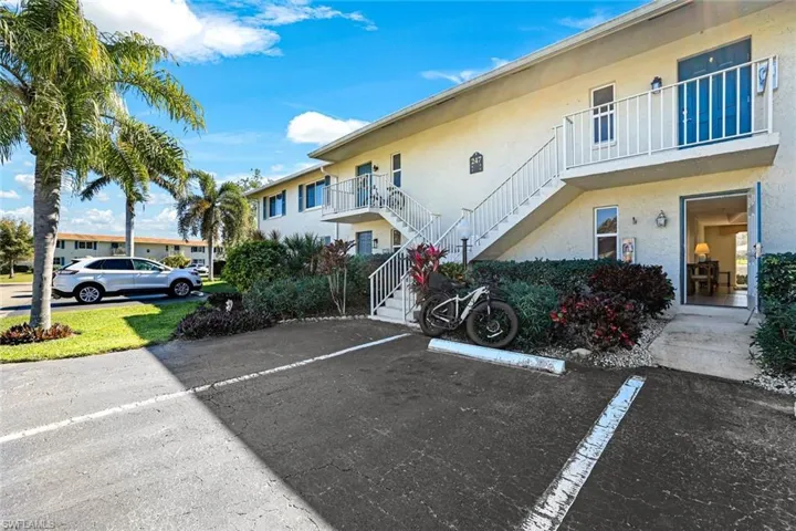 View of building exterior with stairs and uncovered parking