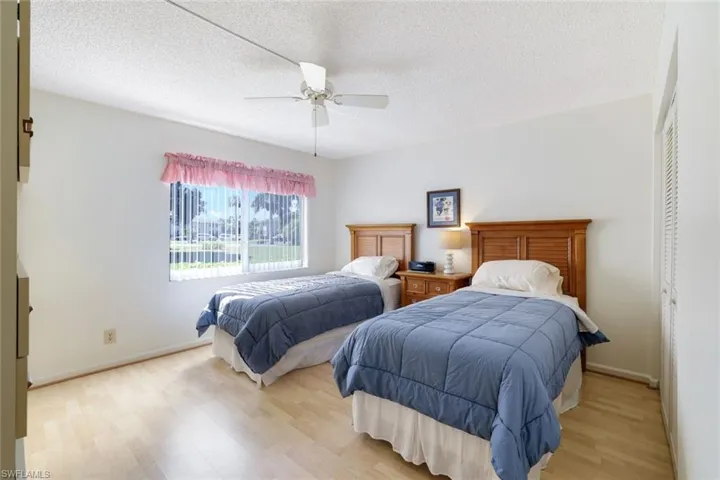 Bedroom with a closet, a textured ceiling, wood finished floors, and a ceiling fan