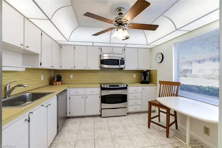 Kitchen featuring stainless steel appliances, light countertops, white cabinetry, and ceiling fan