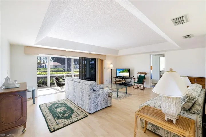 Living room with a raised ceiling, light wood-style floors, and a textured ceiling