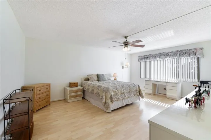 Bedroom featuring light wood-style flooring, a textured ceiling, ceiling fan, and a desk