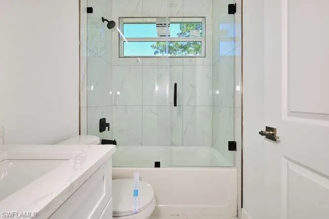 Full bath with combined bath / shower with glass door and vanity