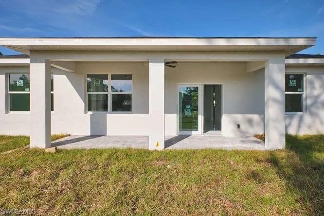 Rear view of property featuring stucco siding, a patio, and a yard