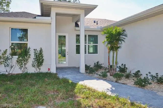 Doorway to property featuring stucco siding and roof with shingles