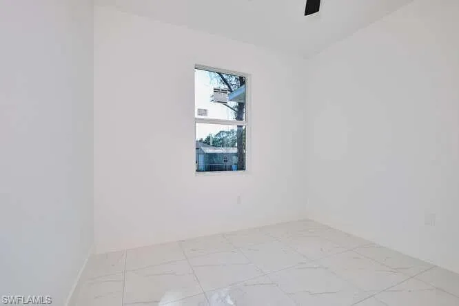 Spare room with light marble finish flooring and baseboards
