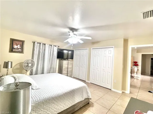 Bedroom featuring multiple closets, light tile patterned flooring, and a ceiling fan