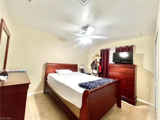 Bedroom with light tile patterned floors and a ceiling fan