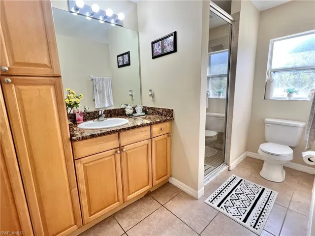 Full bathroom with a stall shower, vanity, and light tile patterned floors