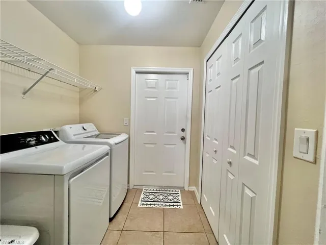 Laundry area with light tile patterned floors and washing machine and dryer