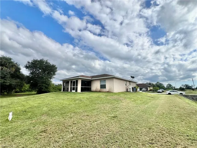 View of home's exterior featuring stucco siding, a lawn, and a sunroom
