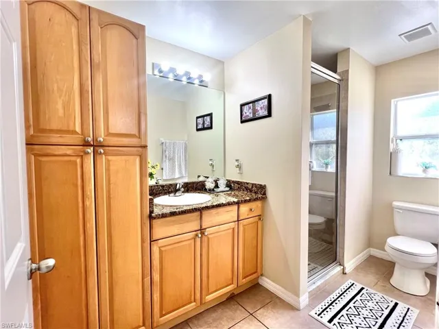 Bathroom with light tile patterned floors, vanity, and a stall shower