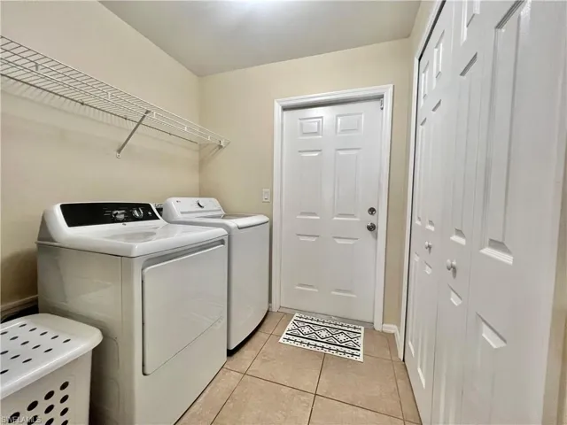 Laundry area with light tile patterned flooring and independent washer and dryer