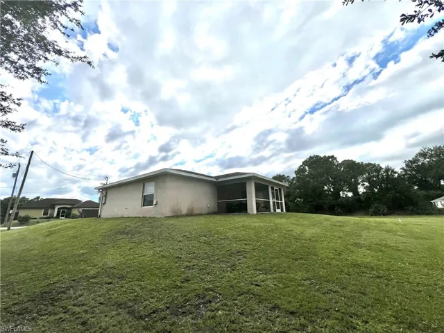 Rear view of property with a lawn, a sunroom, and stucco siding