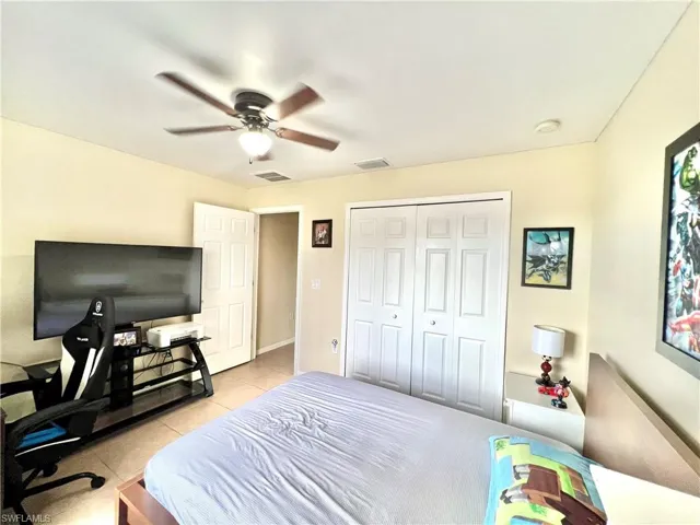 Bedroom featuring light tile patterned floors, a closet, ceiling fan, and a desk