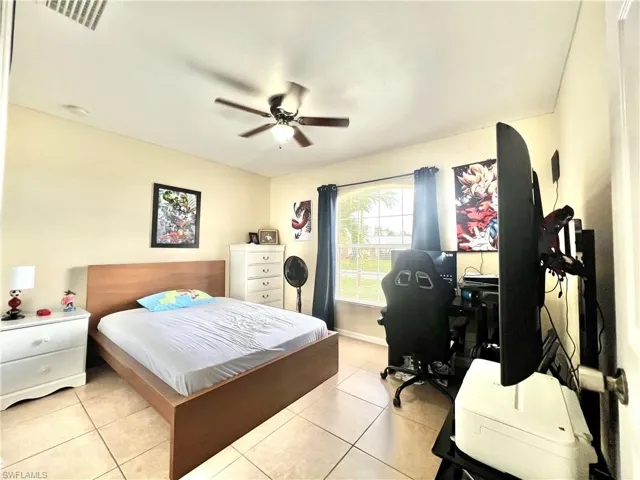 Bedroom with light tile patterned flooring, a ceiling fan, and a desk