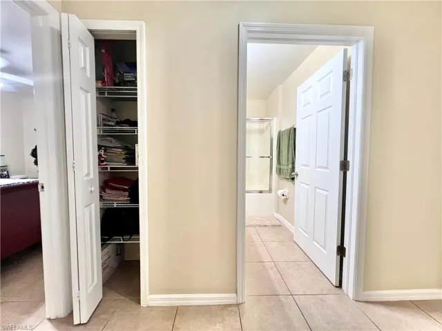 Hallway featuring light tile patterned floors and baseboards