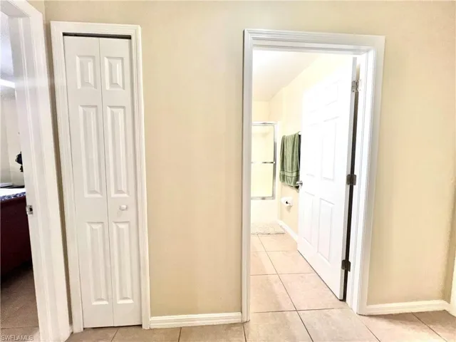 Hall featuring light tile patterned floors and baseboards