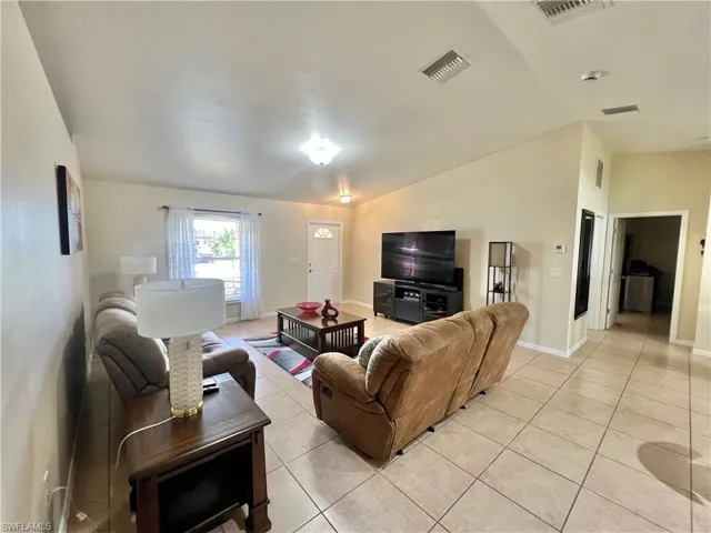 Living area with light tile patterned flooring and vaulted ceiling
