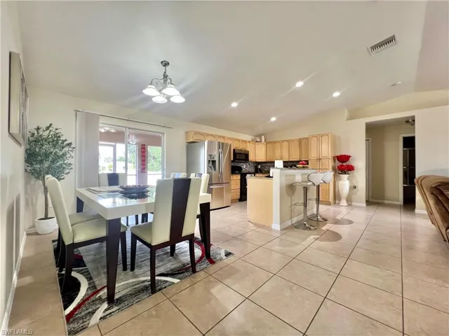 Dining space featuring lofted ceiling, a chandelier, light tile patterned floors, and recessed lighting