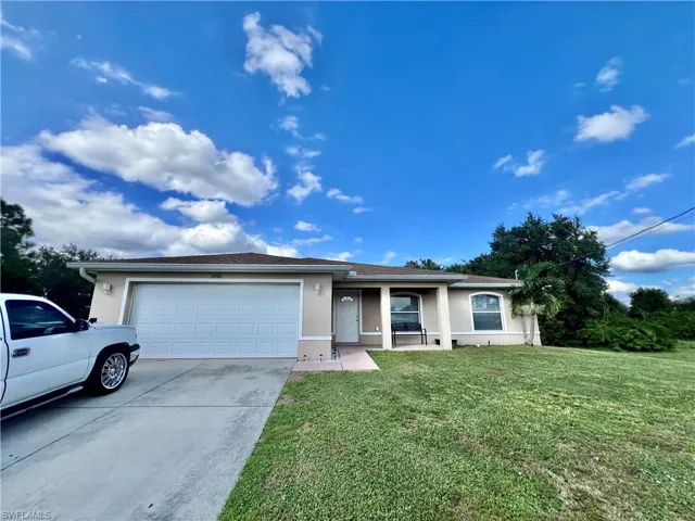Ranch-style home with stucco siding, a front yard, concrete driveway, and a garage