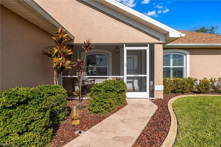 The property features an inviting entrance with a flagstone path, a screened-in porch, and a well-maintained lawn