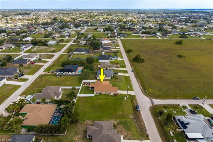 Aerial view of the property, showcasing its surrounding neighborhood and nearby open fields