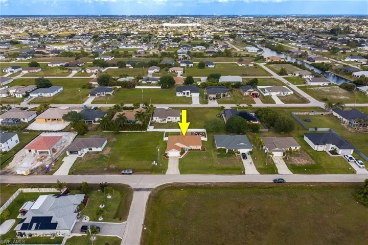 Aerial view of the property, featuring a beige exterior and a driveway