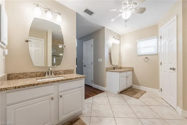 This bathroom features dual vanities with granite countertops, integrated sinks, and white cabinetry