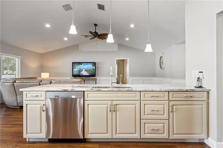 The kitchen features an island with a light-colored countertop, a stainless steel dishwasher, and a sink with a chrome faucet