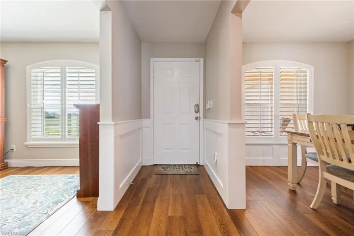 Inviting entryway featuring Lux Vinal wood grain floors, wainscoting, and a white front door