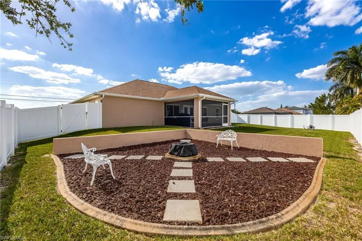 The property features a spacious lawn, a screened-in patio, and a privacy fence, Fire Pit with Electric Outlet