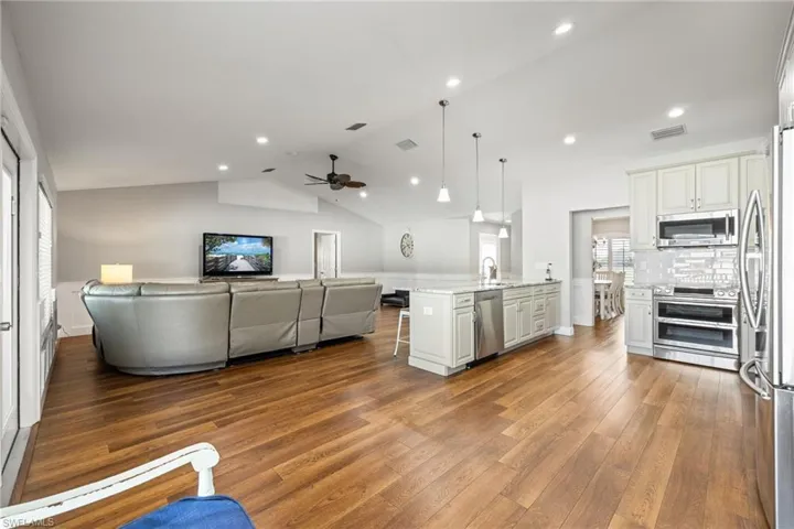Open concept living area featuring LVP wood floors, recessed lighting, and a vaulted ceiling with a ceiling fan