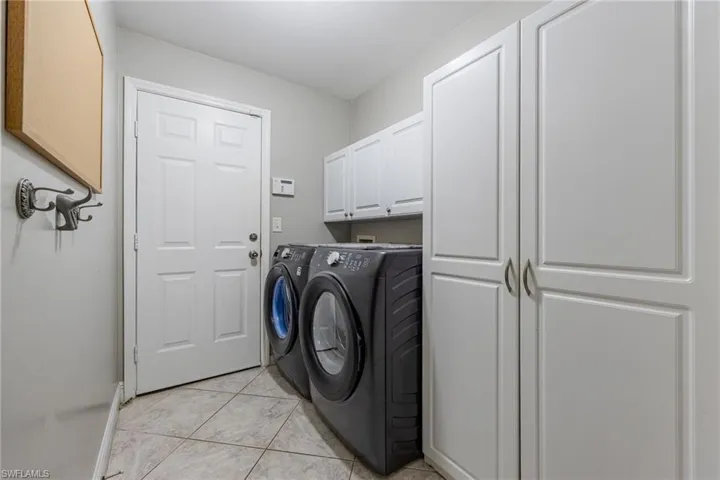 The property includes a dedicated laundry area featuring tile flooring, white cabinetry for storage, and a white paneled door