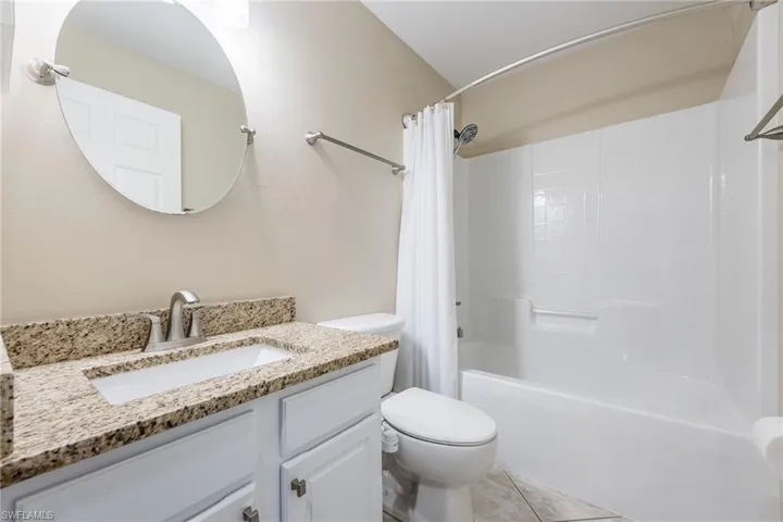 This bathroom features a vanity with a granite countertop, a white rectangular sink, and a brushed nickel faucet