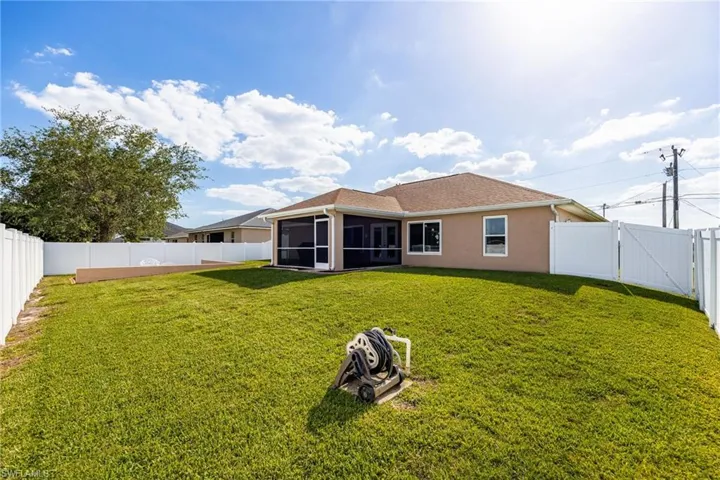 Expansive backyard featuring a well-maintained lawn and a white privacy fence
