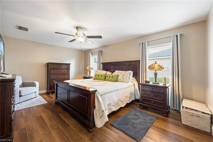 The property features a bedroom with LVP wood grain flooring, a ceiling fan, and a window with blinds and curtains