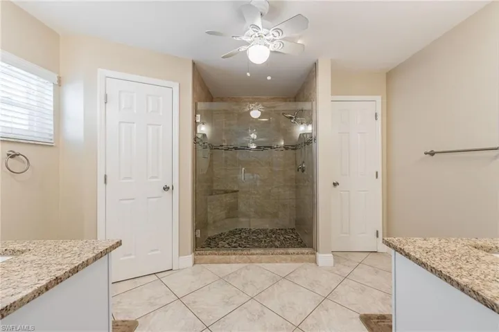 Bathroom featuring a large shower with a glass enclosure, tile walls, and a pebble floor