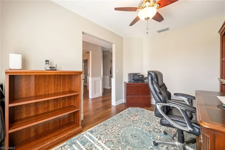 This room features LVP woodgrain flooring, a ceiling fan with integrated lighting, and crown molding