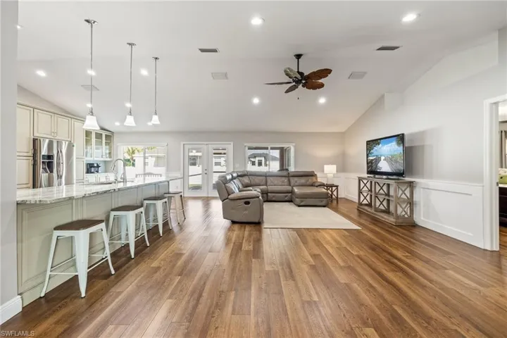 The open concept living area features LVP wood grain flooring, vaulted ceilings, and recessed lighting