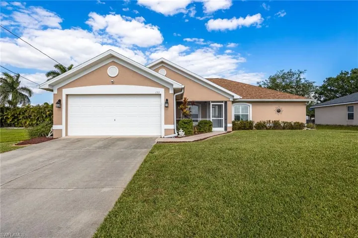 The front of the property features a stucco exterior, an attached garage, a well-maintained lawn, and a driveway