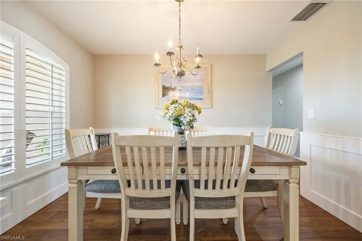 The dining area features LVP woodgrain floors and wainscoting, complemented by a chandelier