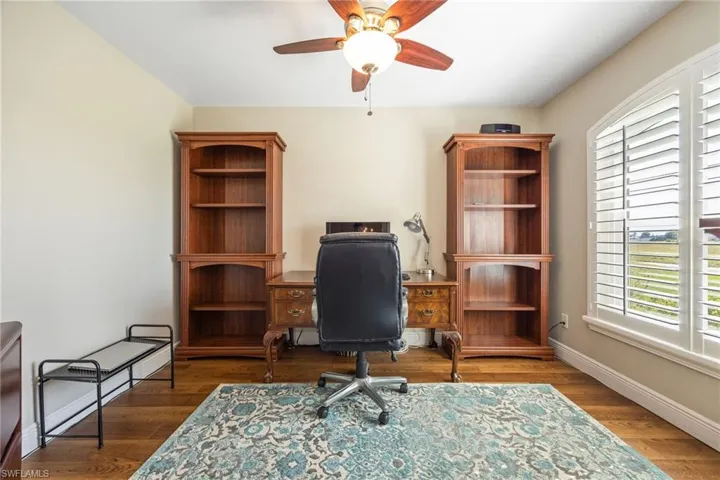 This room features LVP woodgrain floors, a ceiling fan with light fixture, and a window with plantation shutters