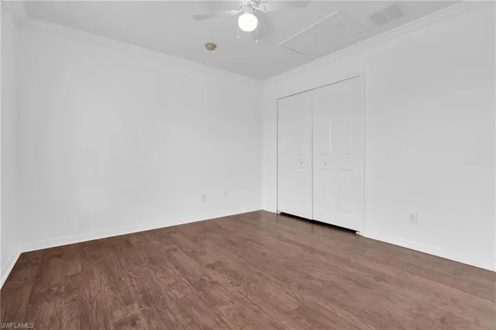 Unfurnished bedroom with crown molding, dark wood finished floors, a closet, and ceiling fan