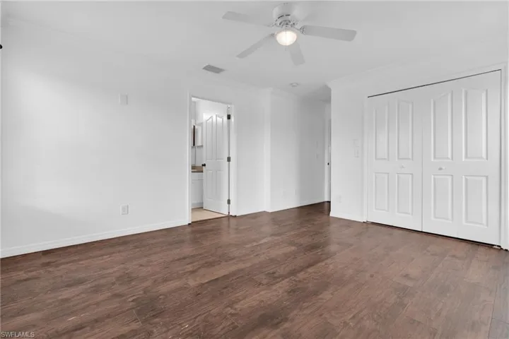 Unfurnished bedroom featuring ornamental molding, dark wood-type flooring, a closet, and ceiling fan