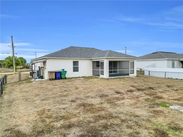 Rear view of house with a fenced backyard, stucco siding, a gate, a sunroom, and roof with shingles