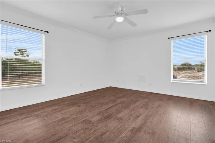 Unfurnished room with ornamental molding, dark wood-style floors, and ceiling fan